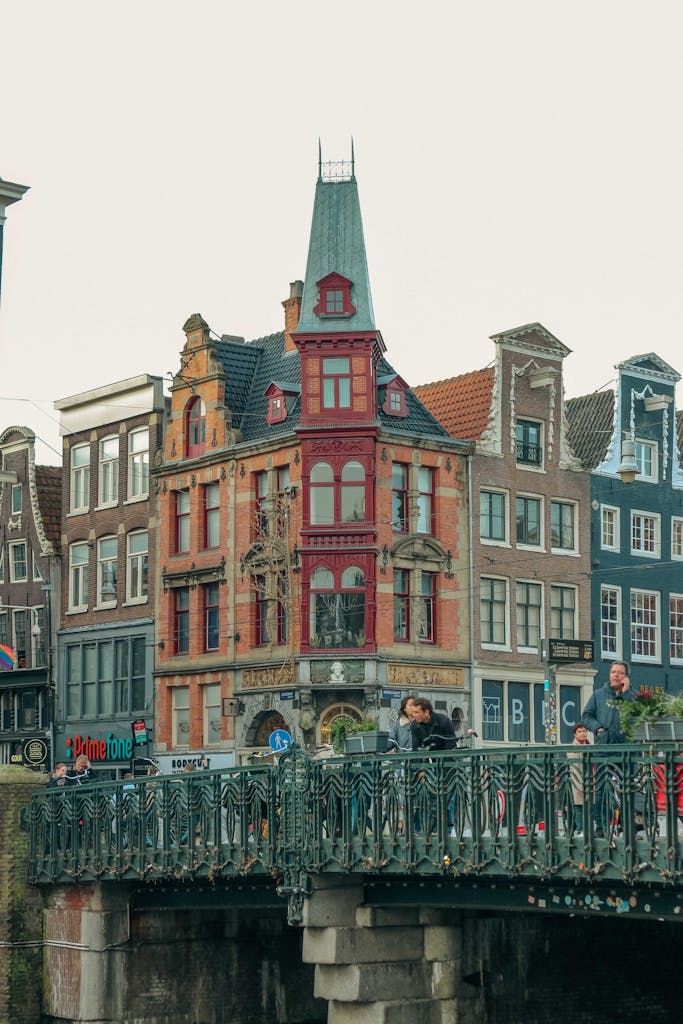 Picturesque Amsterdam canal scene featuring a historic bridge and colorful buildings with people walking.