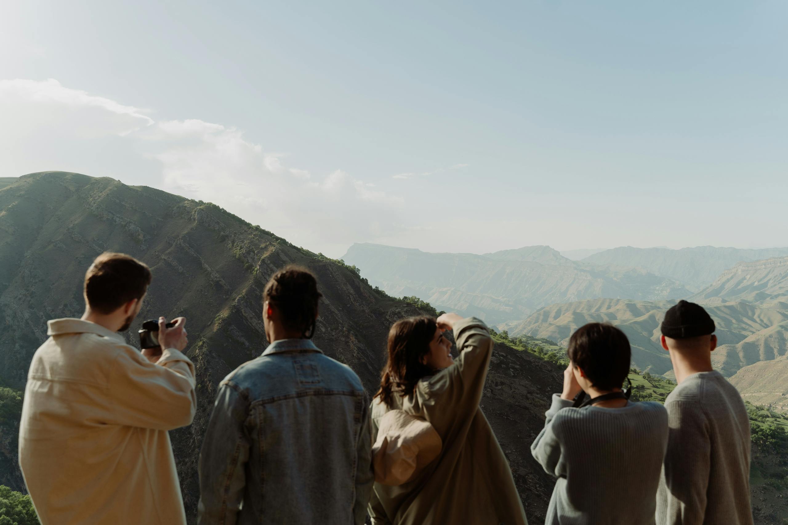 A group of friends observing a scenic mountain view on a sunny day