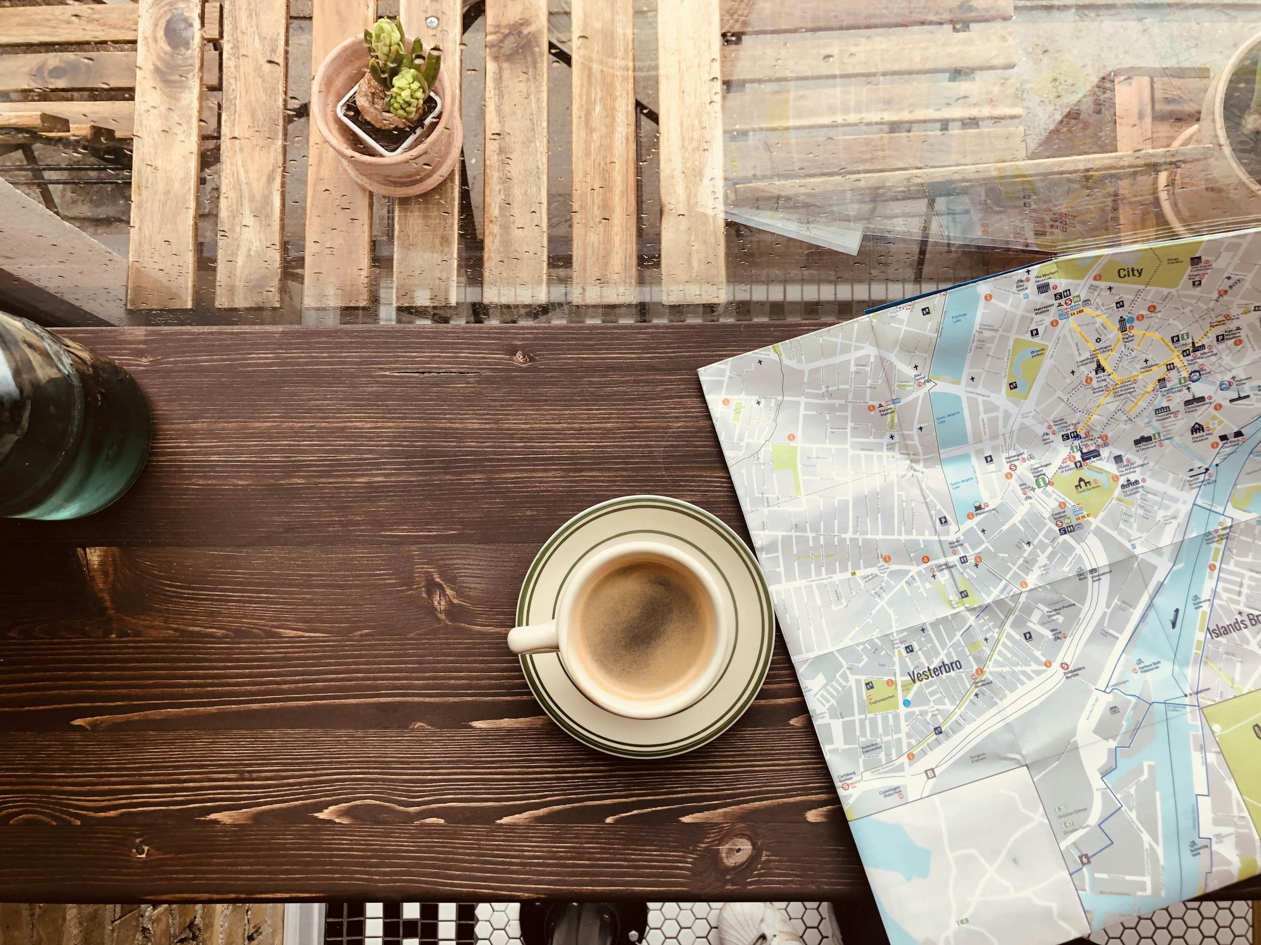 Cup of coffee and a city map on a wooden table by the window in copenhagens cozy cafe
