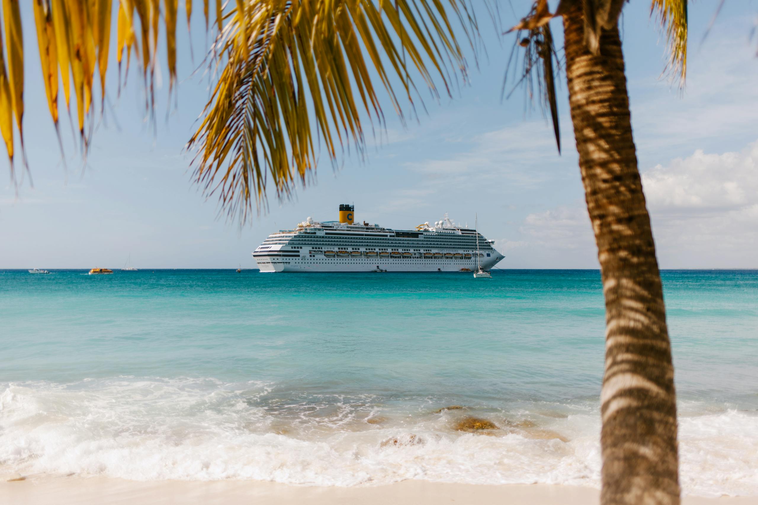 Tropical beach view with cruise ship and palm tree in turquoise waters